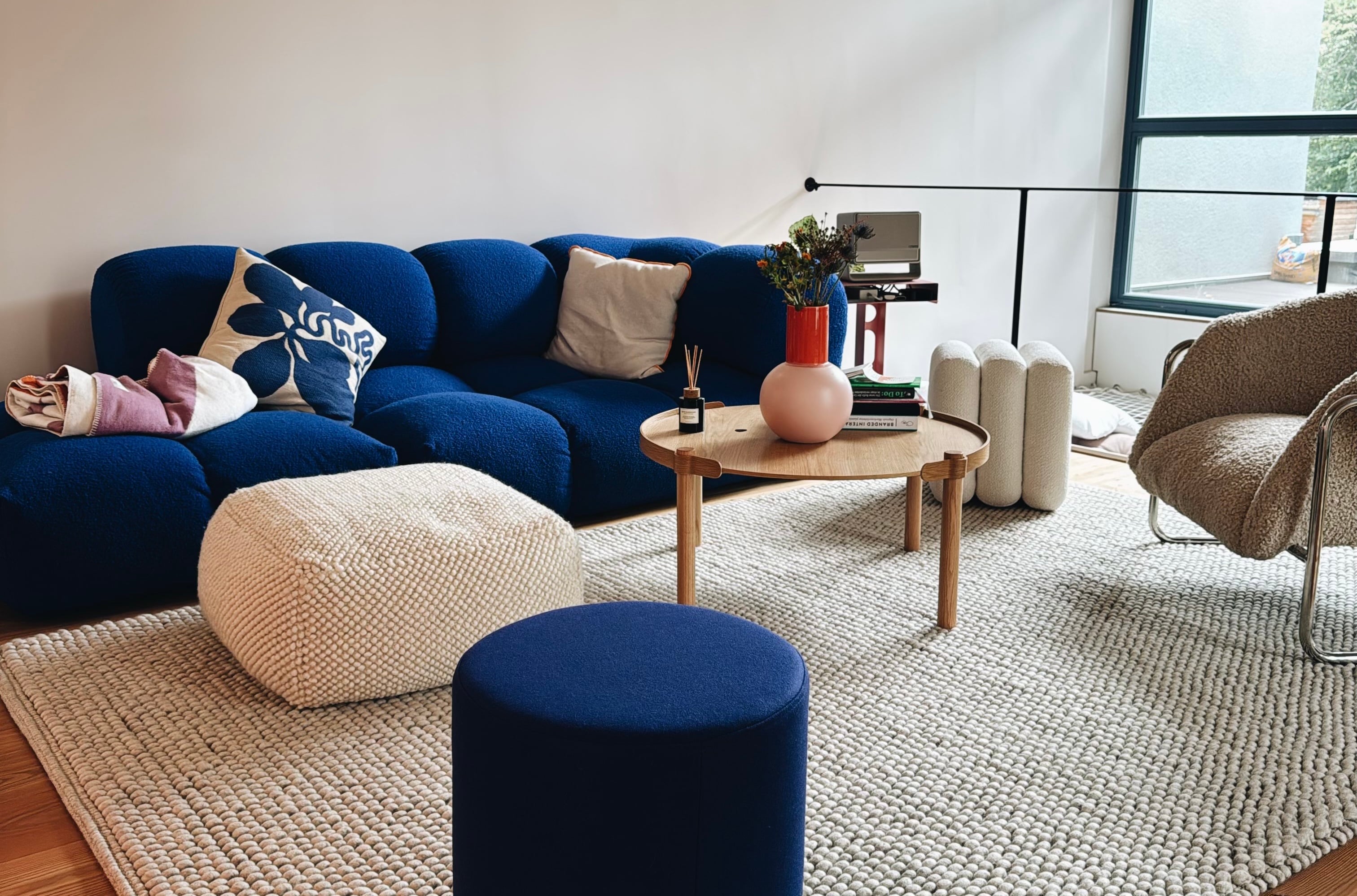Das Loft: blaues Sofa, Sessel, runder Tisch auf dem Teppich