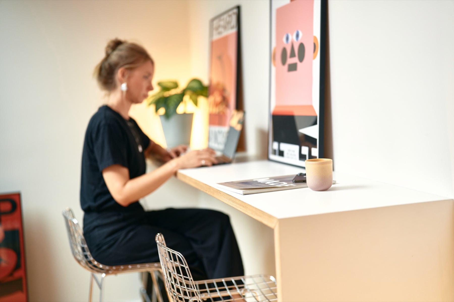 Eine Frau arbeitet am Schreibtisch vor Postern