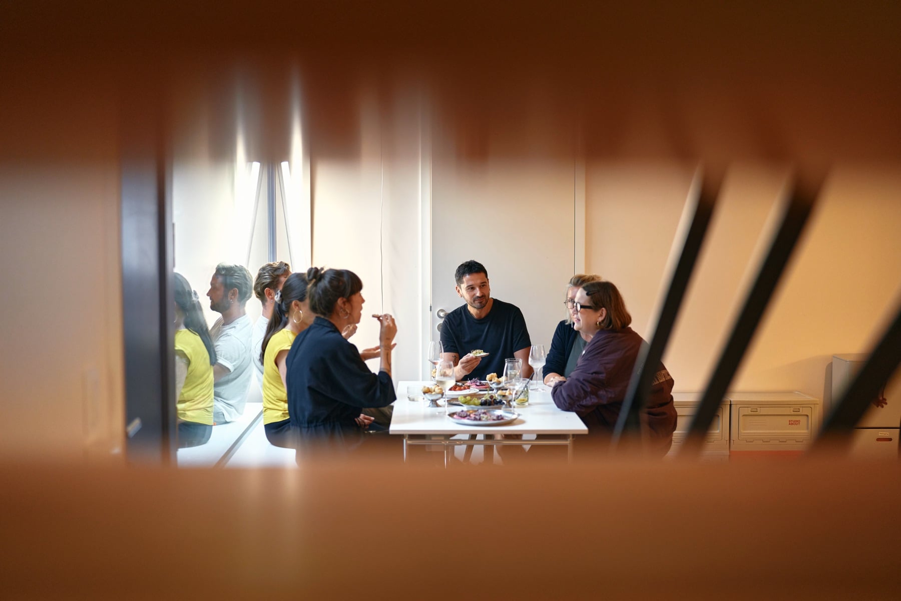 A group at the table, seen through the slats of the stairs