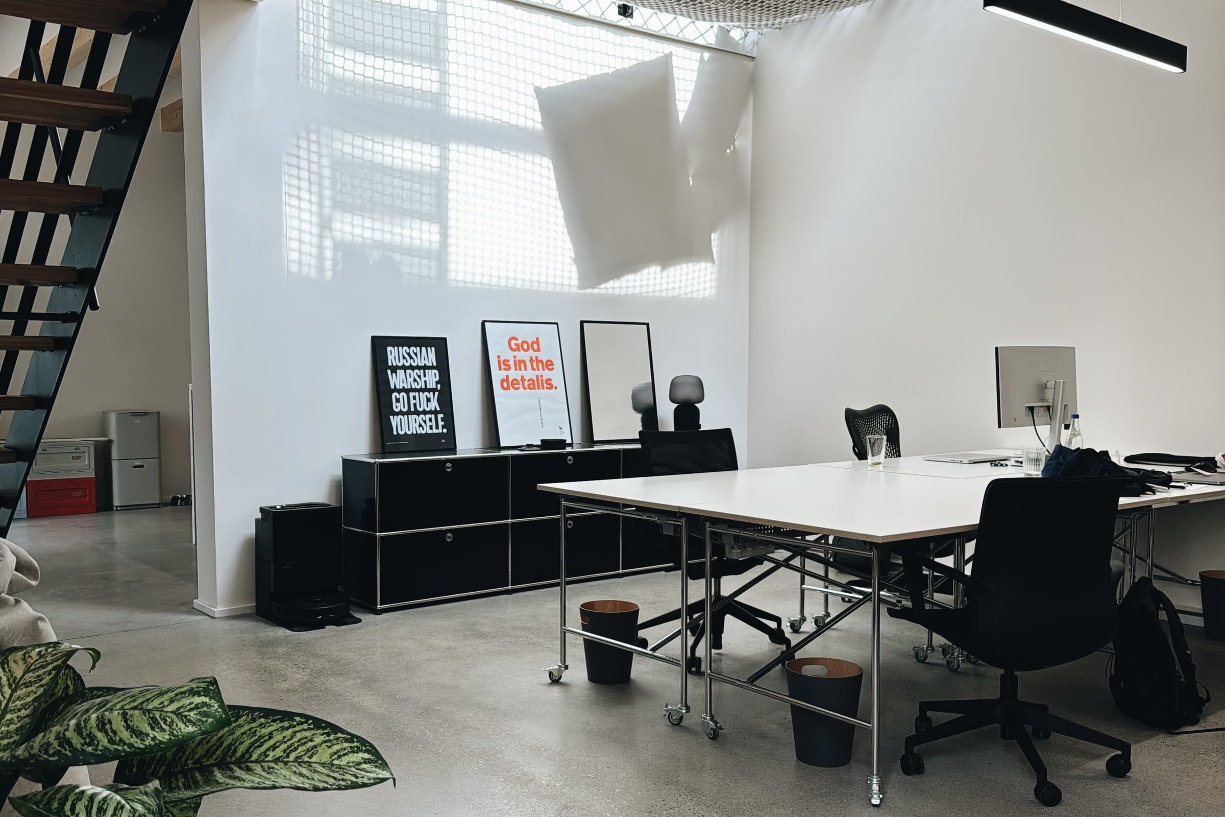 The ground floor at tribehouse: Eiermann tables, a net under the ceiling, posters and the staircase