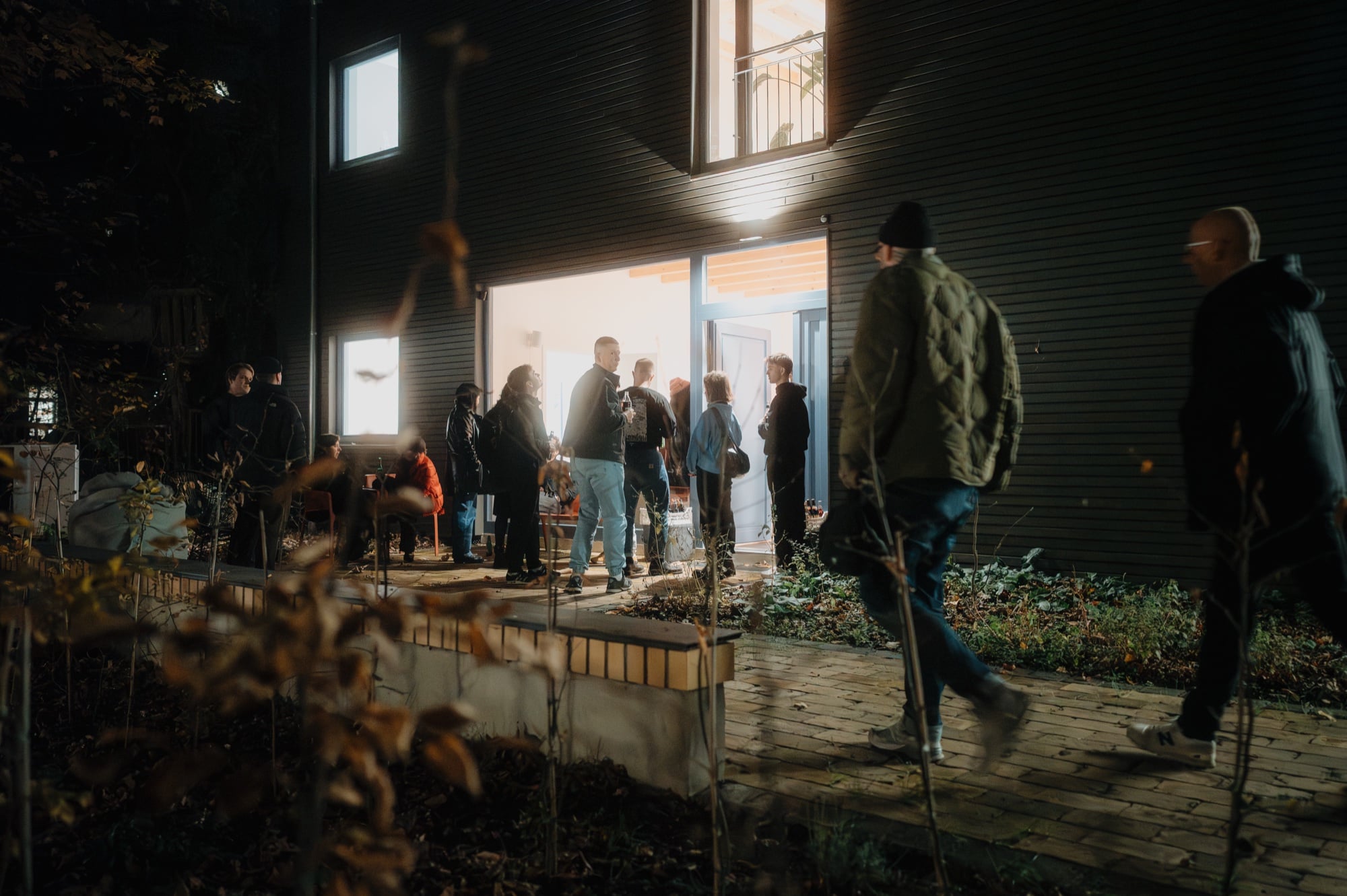 Gäste im Hinterhof vor dem beleuchteten Eingang