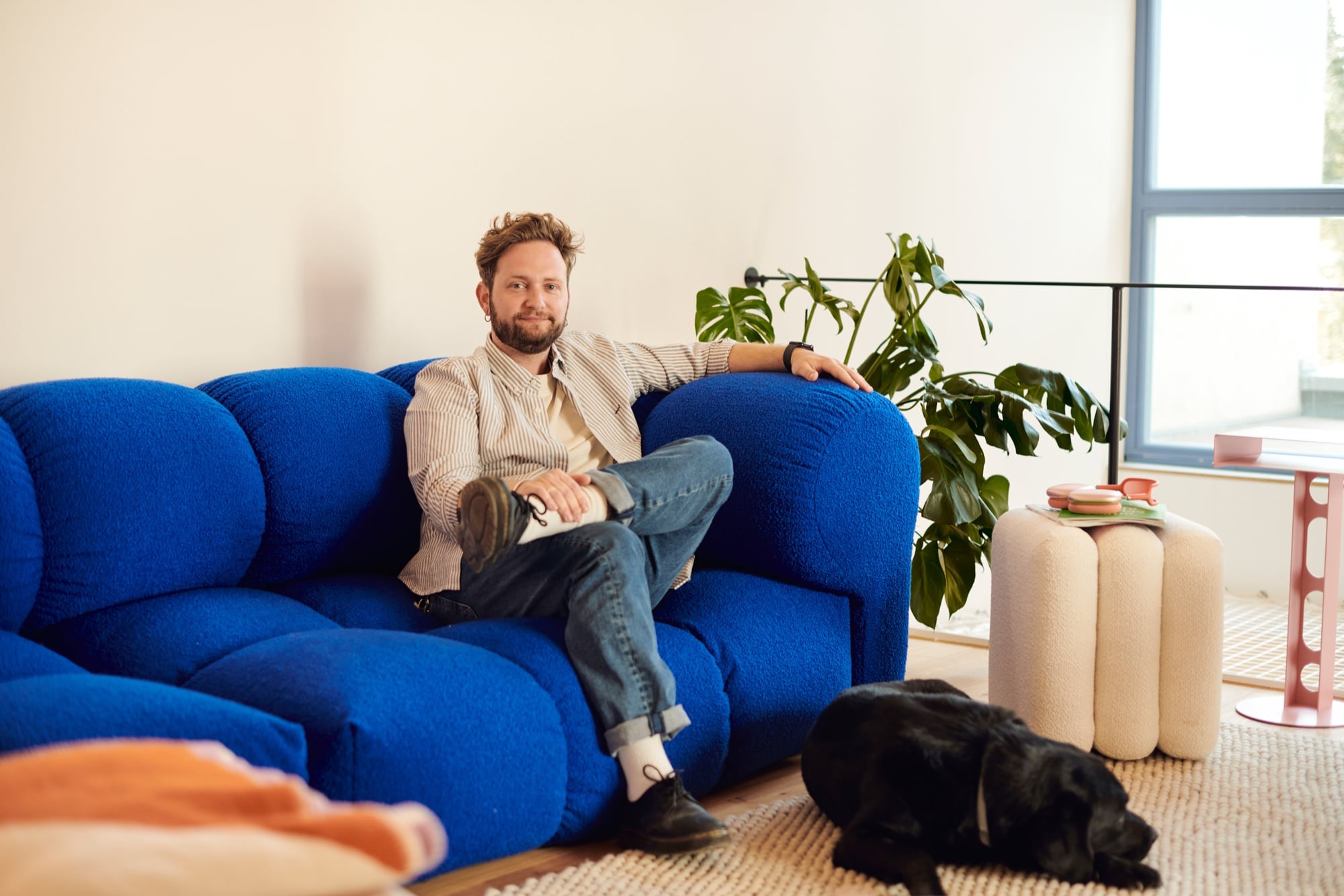 Justin auf dem blauen Sofa im Loft, Räuber liegt auf dem Teppich